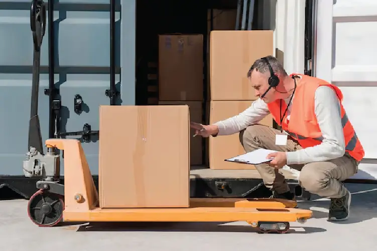 A worker in a blue uniform in a warehouse aisle amongst shelves of boxes, illustrating safe and secure freight handling